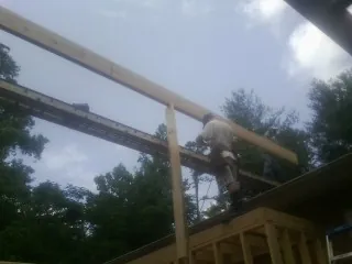 Carpenter setting a ridge beam over a new addition frame — Ice Dam Removal by Roofing Brothers in Ocheyedan
