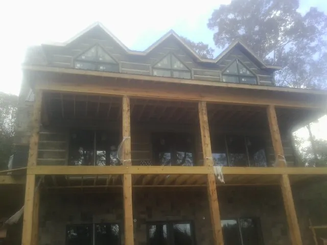 Dormers and porch framing on a large log home under construction — Roof Coating work by our crew in Ocheyedan