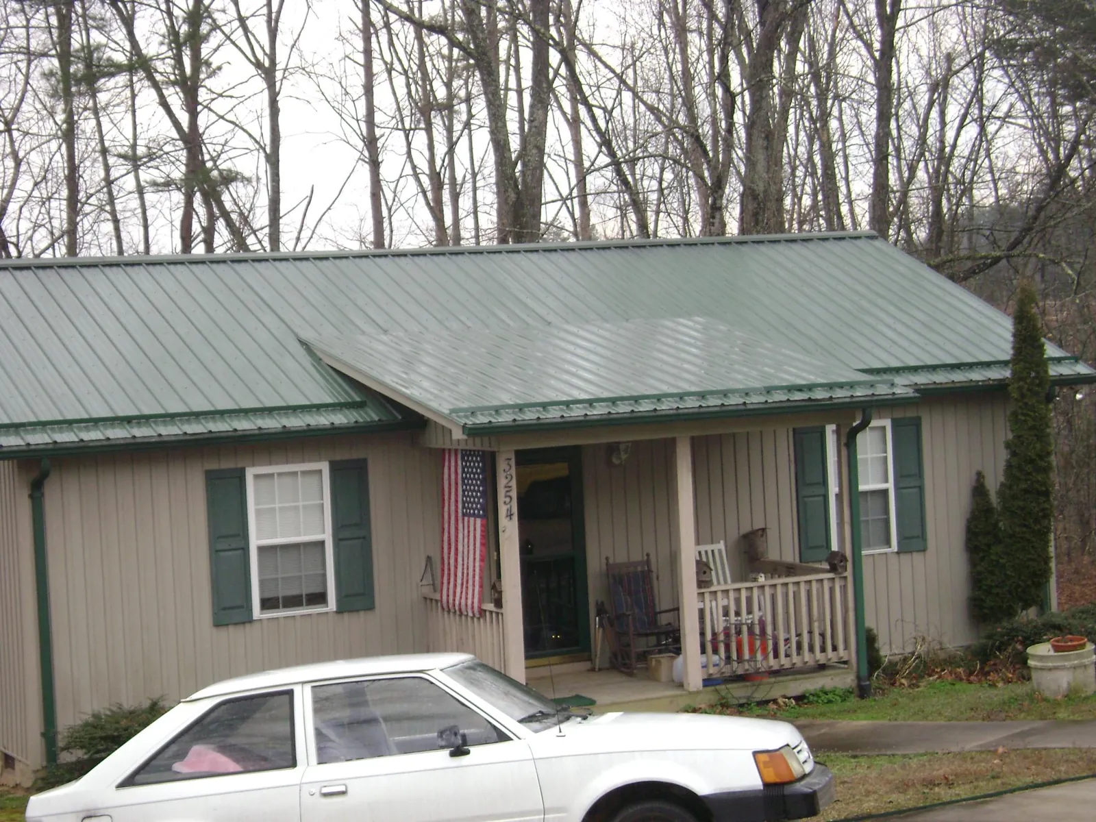 Green metal roof and front porch on a tan sided cottage in Ocheyedan