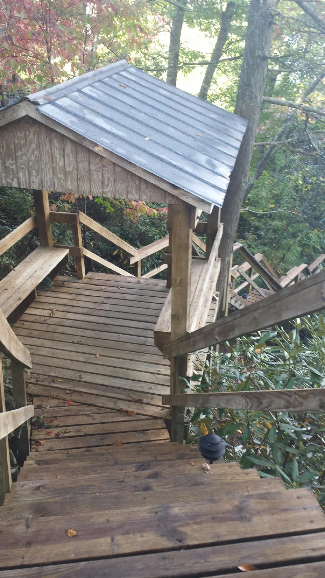 Metal roofed shelter over wooden steps on a wooded walkway — Skylight Repair & Installation work by our crew in Ocheyedan