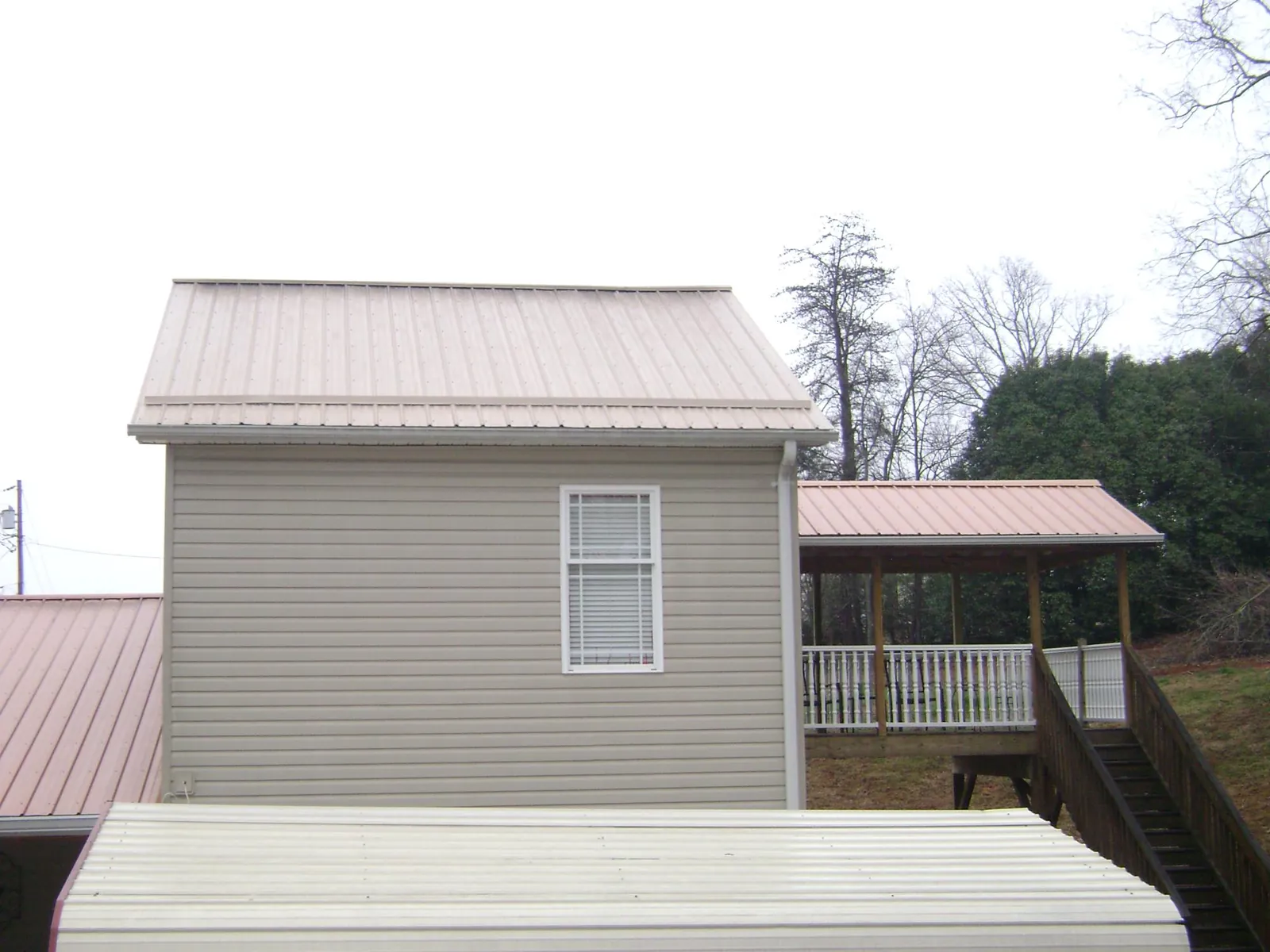 Tan metal roofs on a two story addition and attached porch, from a Roof Replacement job in Ocheyedan